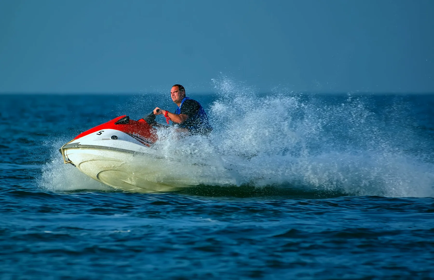 Moto de agua roja y blanca levantando una gran estela de espuma